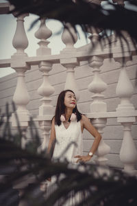 Portrait of young woman sitting on railing