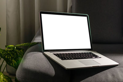 Close-up of laptop on sofa