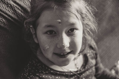 Close-up portrait of smiling girl with paints on her face at home