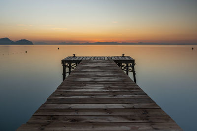 Pier over sea against sky during sunset