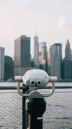 Close-up of coin-operated binoculars against buildings in city