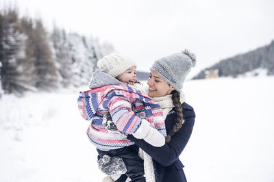 Happy mother carrying daughter in winter landscape