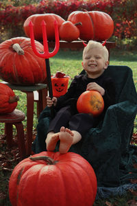 Full length of a boy with pumpkins on field
