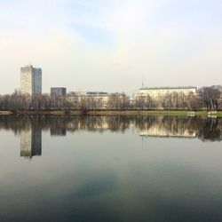 Reflection of buildings in lake against sky in city