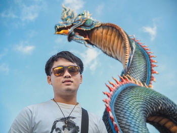 Portrait of young man against sculpture and sky