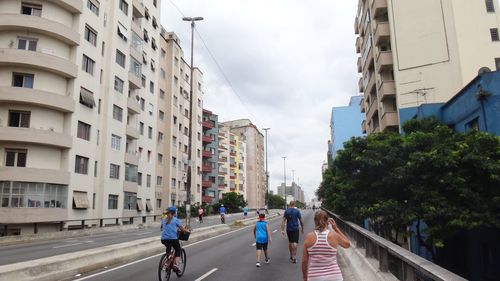 View of people walking and biking on road in city