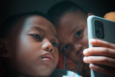 Close-up of brothers using smart phone at home