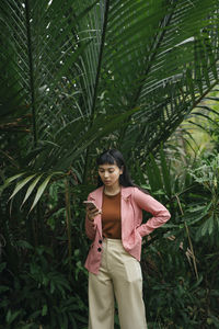 Young woman standing by tree