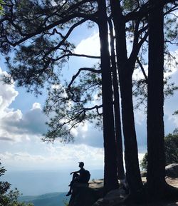 Side view of silhouette man sitting cliff 