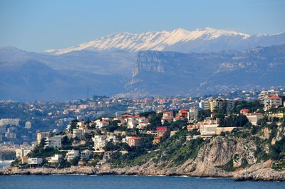 View of city by sea and mountains against sky