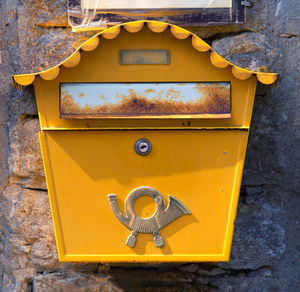 Close-up of yellow mailbox on wall