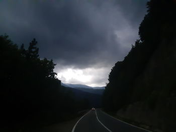 Road amidst trees against sky