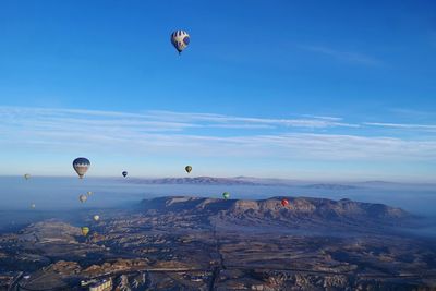 Hot air balloons flying over cappadocia against blue sky