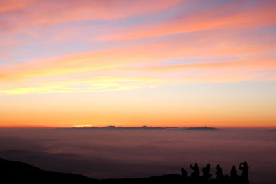 Silhouette people at mountain against sky during sunrise