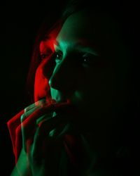 Close-up portrait of young woman against black background