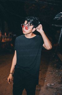 Young man looking away while standing on street at night