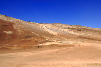 Scenic view of desert against clear blue sky