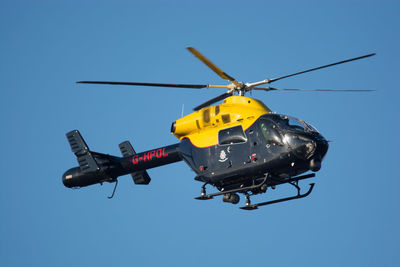 Low angle view of helicopter against clear blue sky