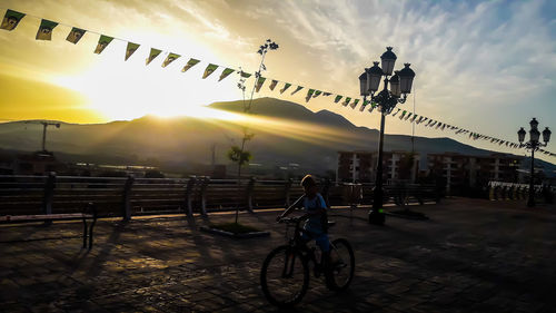 Bicycles on street against sky during sunset