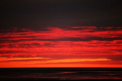 Scenic view of sea against dramatic sky during sunset