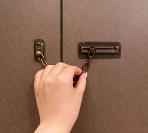 Cropped hand of person holding padlock on wall