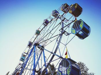 Low angle view of ferris wheel against clear blue sky