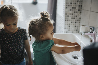 Sisters washing hands in bathroom