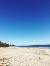 Scenic view of beach against clear blue sky