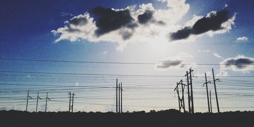 Low angle view of electricity pylon against blue sky