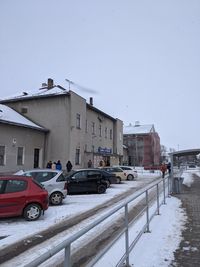 Cars on street by buildings in city against clear sky