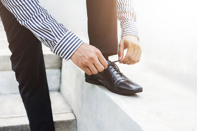 Low section of man tying shoelace