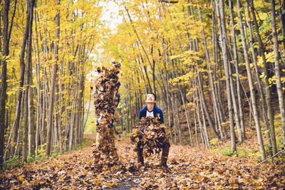 Happy brothers throwing dry leaves in mid air at forest