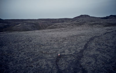 Aerial landscape of red house in dark dry terrain surrounded by hills