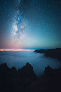 Breathtaking scenery of rocky hill and foamy sea under sunset sky in long exposure milky way starry night