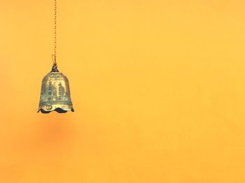 Bell hanging against orange wall