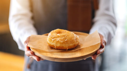 A waitress holding and serving a piece of homemade donut in wooden tray