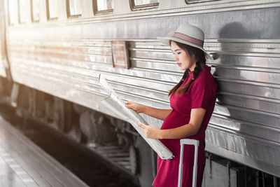 Side view of young woman standing against building