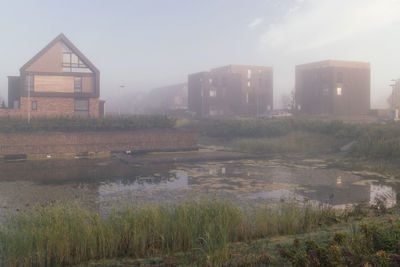 Buildings by lake in city against sky