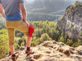 Hiker stays on a rocky ridge and enjoy view over long valley to horizon