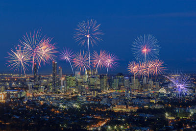 Firework display in city against sky at night