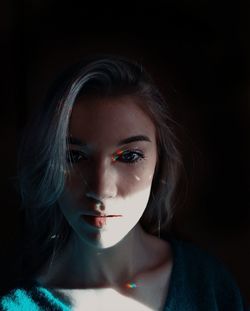 Close-up portrait of young woman in darkroom