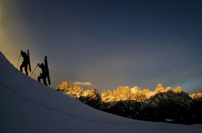 People on snowcapped mountain against sky during winter