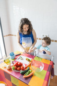 Woman preparing food while standing with son