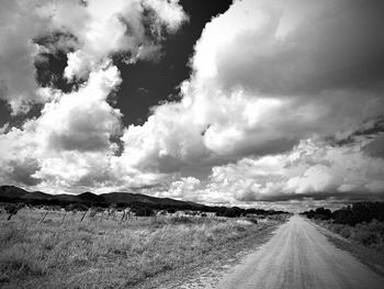 Panoramic view of road amidst field against sky