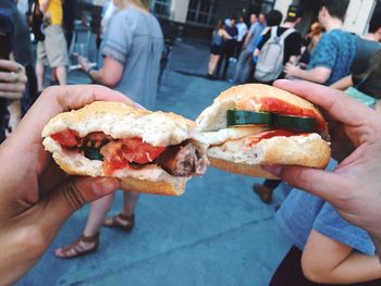 Cropped image of hands holding sandwich on street