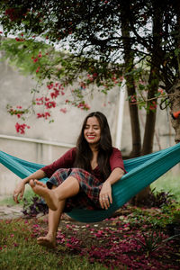 Portrait of smiling young woman sitting against plants