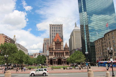 Low angle view of trinity church and modern glass buildings in front of road in city