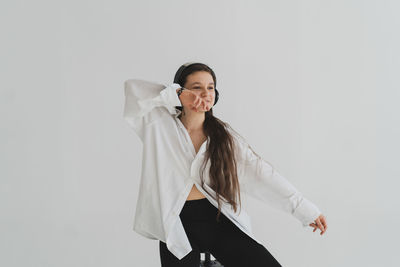 Portrait of young woman standing against white background