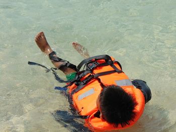 High angle view of boy wearing life jacket swimming in sea