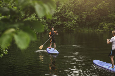 Senior woman and man learning paddleboarding in sea during sup course